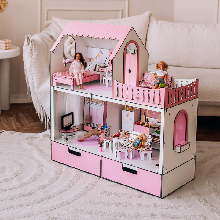 Cardboard dollhouse with pink accents in a room with a sofa and decorative elements.