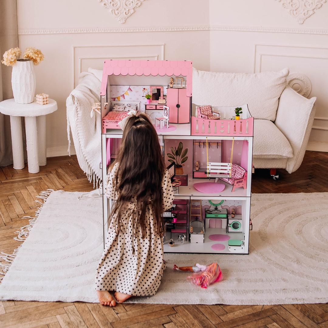 Child playing with a pink toy kitchen set in a room with decorative walls and a white sofa.
