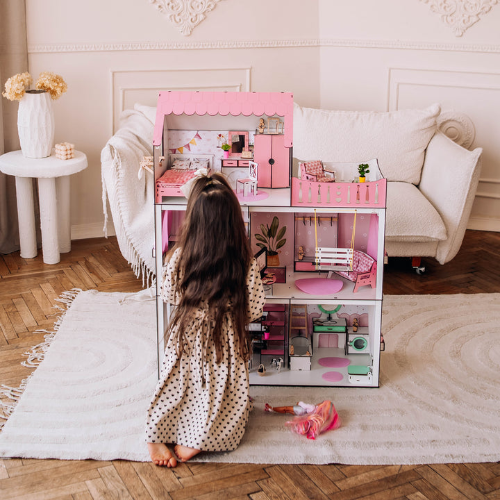 Child playing with a pink toy kitchen set in a room with decorative walls and a white sofa.