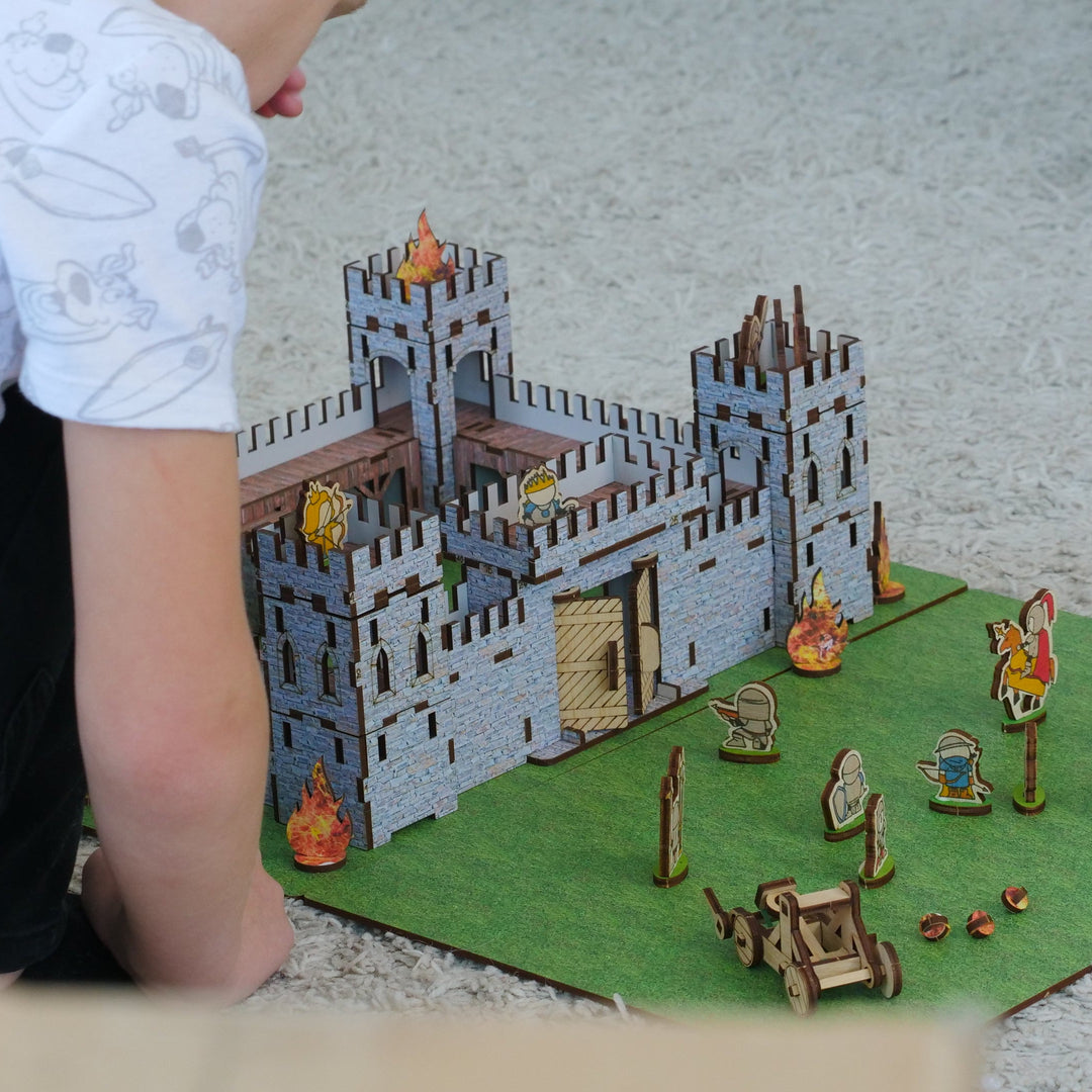 Child playing with a toy castle set on a green mat