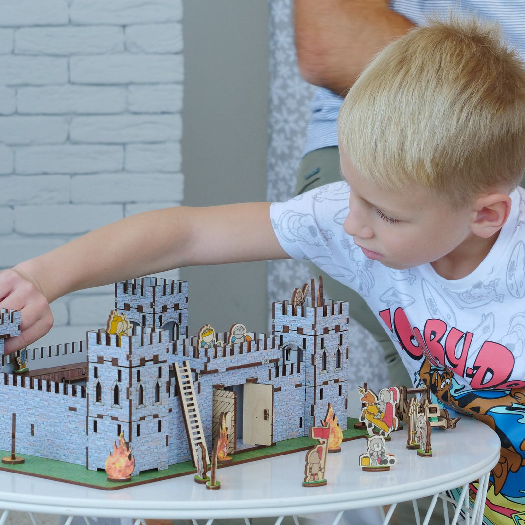 Child playing with a toy castle set on a small table.