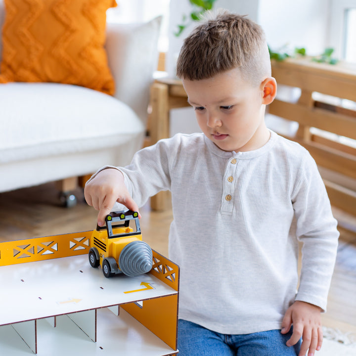 Child playing with a toy garage set in a room, featuring Nestwood branding.