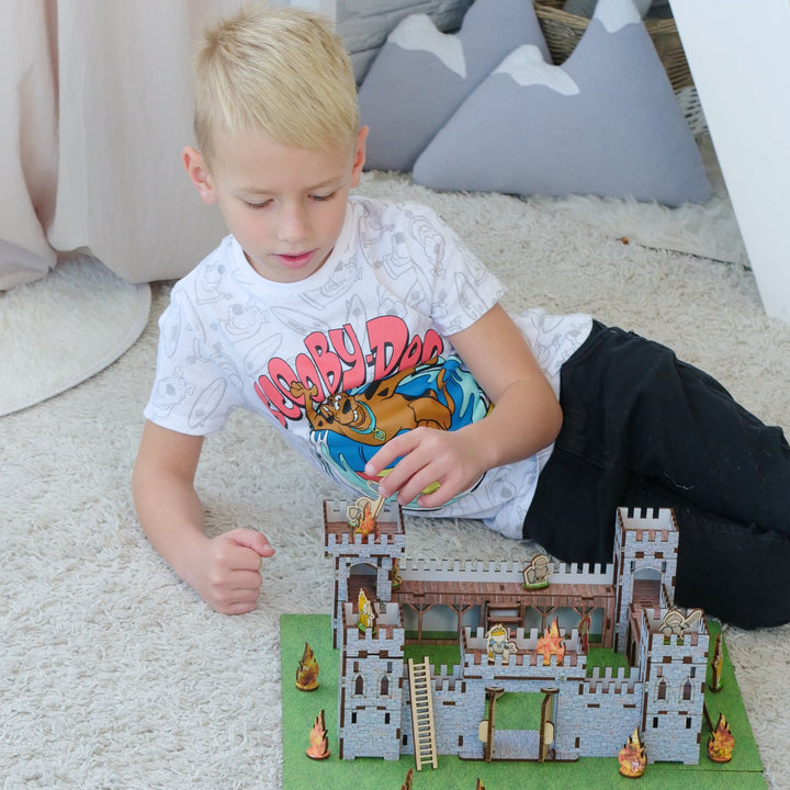Child playing with toy building set on a green mat outdoors