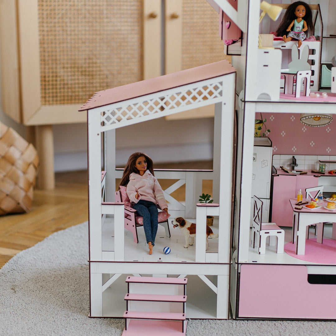 Dollhouse with a doll sitting on a chair inside, surrounded by furniture and decor.