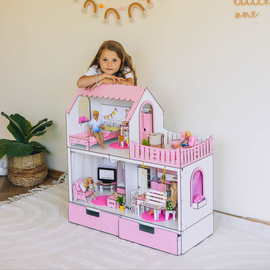 Child playing with a pink dollhouse in a room with decorative elements.