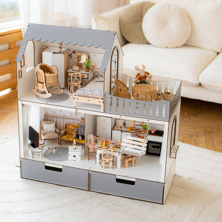 Detailed dollhouse with furniture on a white surface, with a couch and window in the background.
