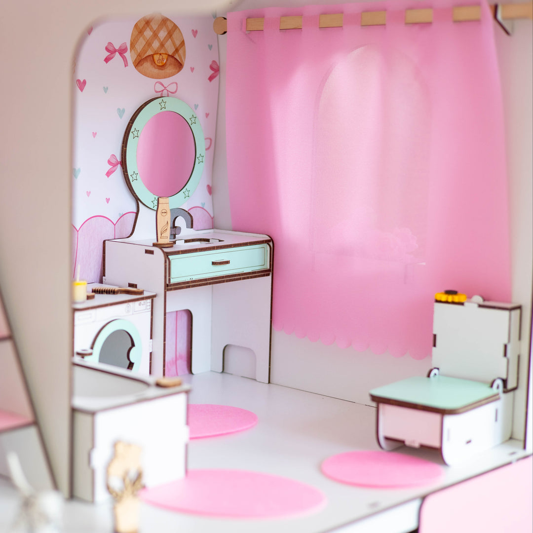 A dollhouse-style miniature bedroom set with a blonde Barbie doll in a green patterned dress, pink curtains, a vanity with a mirror, a small toilet, and shelving, shown in a soft-focus lifestyle presentation.