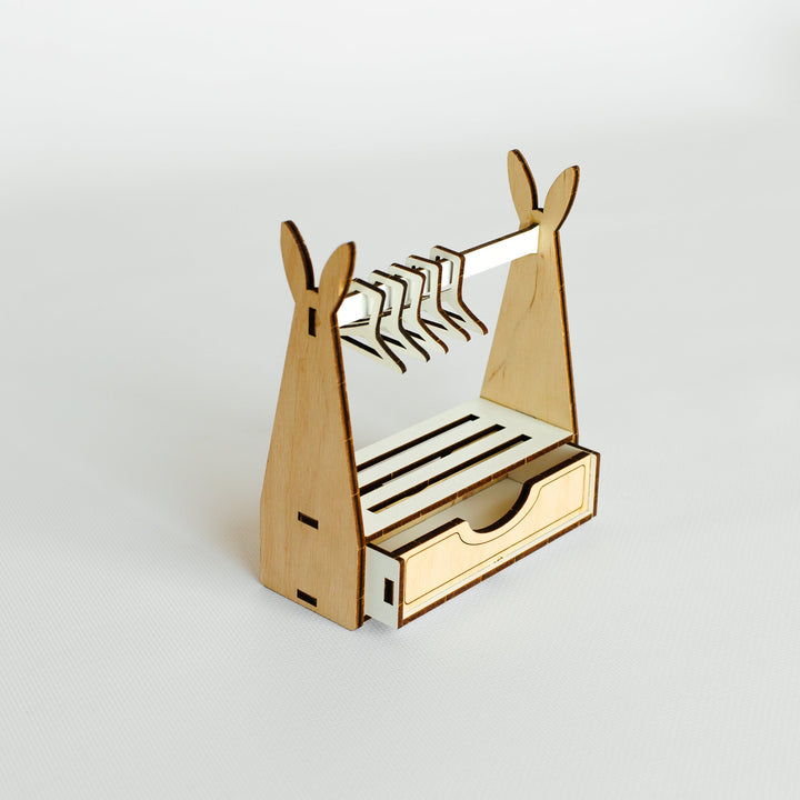 A small wooden bunny-shaped hanger stand with a top clothing rack, slatted shelf, and a front drawer, shown on a clean light gray background.