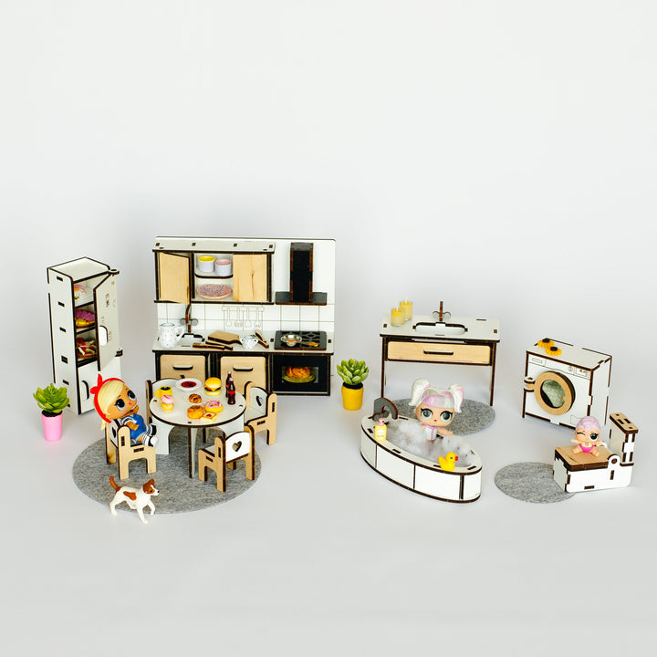 A miniature dollhouse-style kitchen and living room set with small furniture pieces, appliances, plants, and tiny figurines on a plain light gray background.