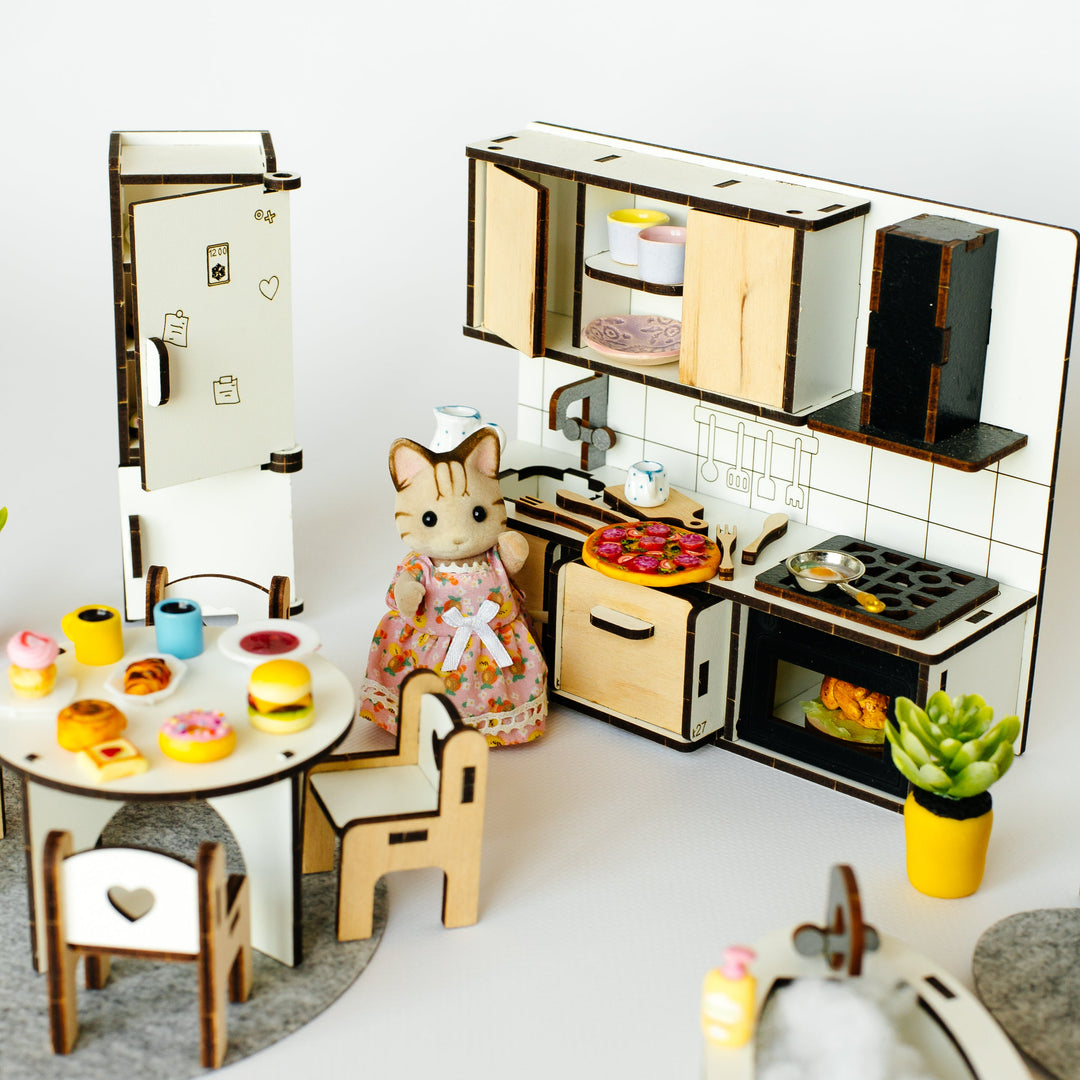 A miniature dollhouse-style kitchen and dining set with tiny furniture pieces, a small cat figurine, toy food, and a bathtub, photographed on a clean white background.