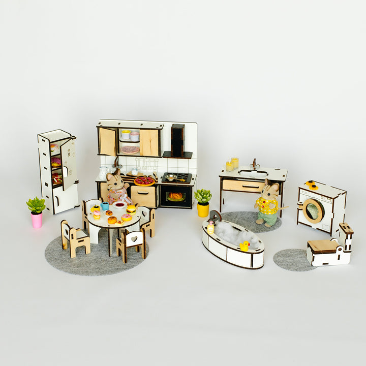 A miniature dollhouse kitchen and dining set with small furniture pieces, appliances, and decor arranged on a light gray background.