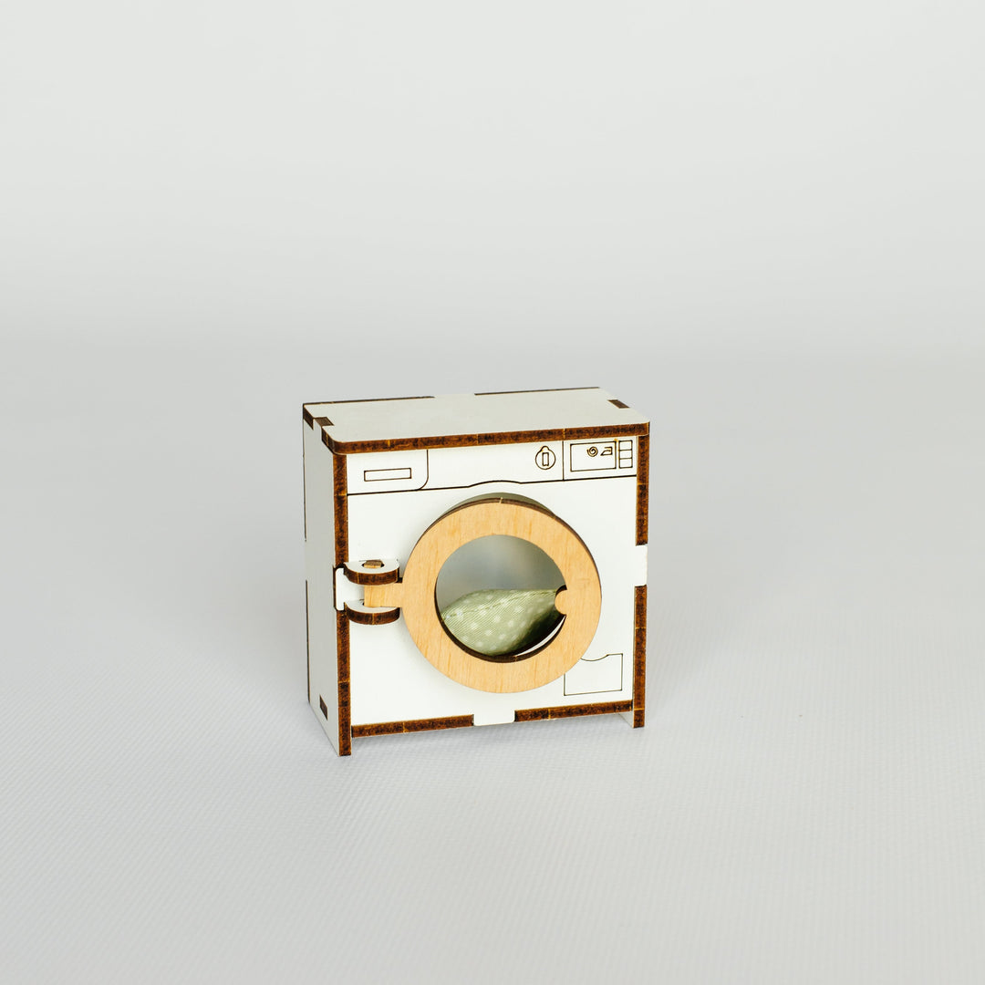 A miniature wooden model of a washing machine, likely a laser-cut craft kit, shown on a neutral light gray background.