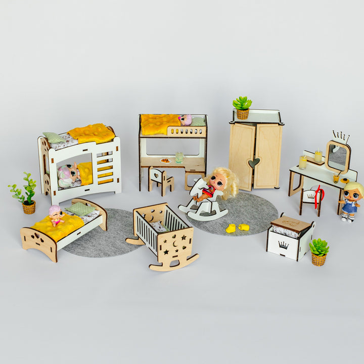 A miniature wooden dollhouse nursery furniture set arranged on a light gray background. The set includes a white and wood crib, a wooden rocking horse, a wooden changing table, a wooden wardrobe, a wooden desk with a vanity mirror, a wooden changing bed, and small potted plants.