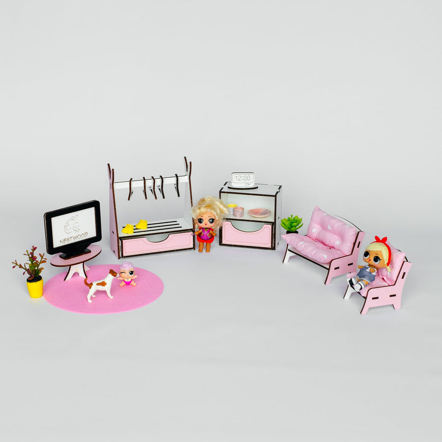 A miniature dollhouse living room set featuring a pink sofa, chair, TV stand with a monitor, clothing rack, and small character figures, arranged on a light gray background.
