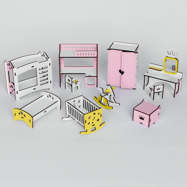 A set of miniature wooden dollhouse furniture pieces, including a bed, crib, wardrobe, desk, and chairs, in pastel pink, white, and yellow colors, arranged on a light gray background.