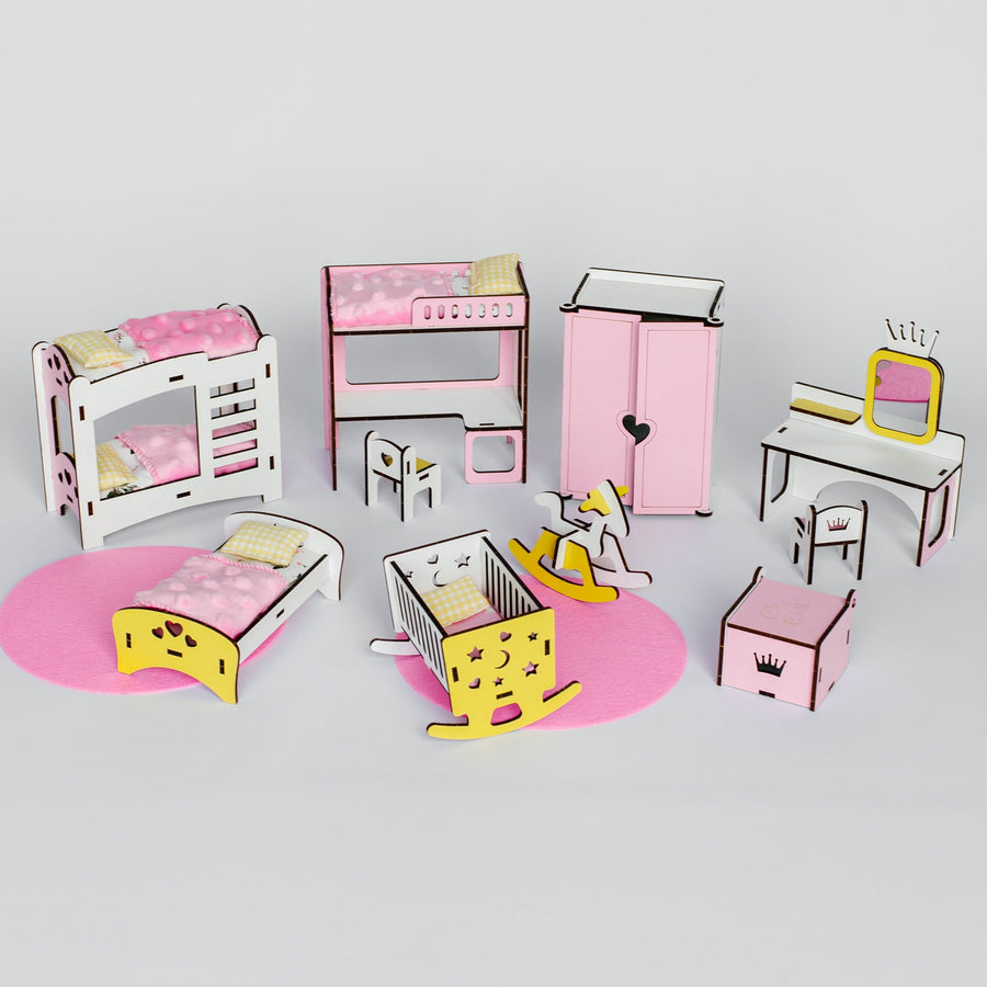 A dollhouse or miniature furniture set arranged on a light gray background, including pink and white beds, a dresser, wardrobe, desk with mirror, rocking horse, and small storage boxes.