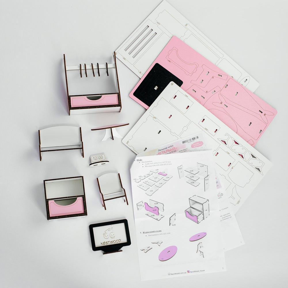 A miniature furniture assembly kit with various small wooden frames, pink drawer inserts, and instruction sheets laid out on a white surface.
