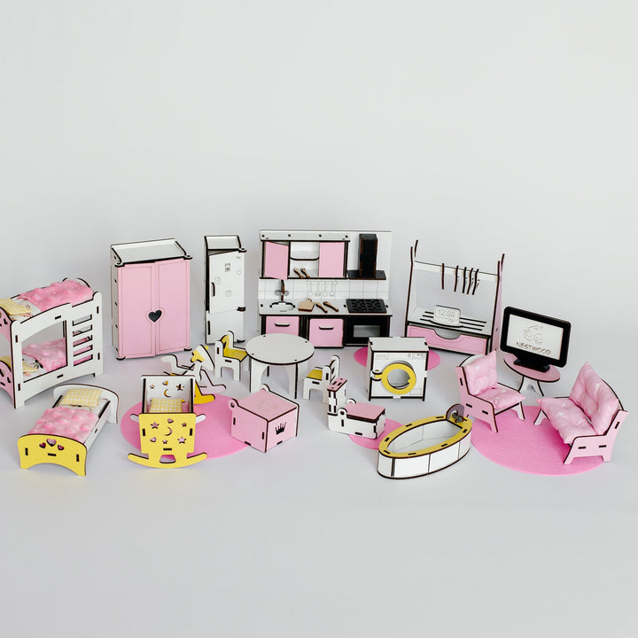 A dollhouse-scale miniature bedroom furniture set arranged on a light gray background. The set includes pink and white furniture pieces such as a bed, wardrobe, desk, chairs, sofa, and kitchen cabinetry, along with small accessories.