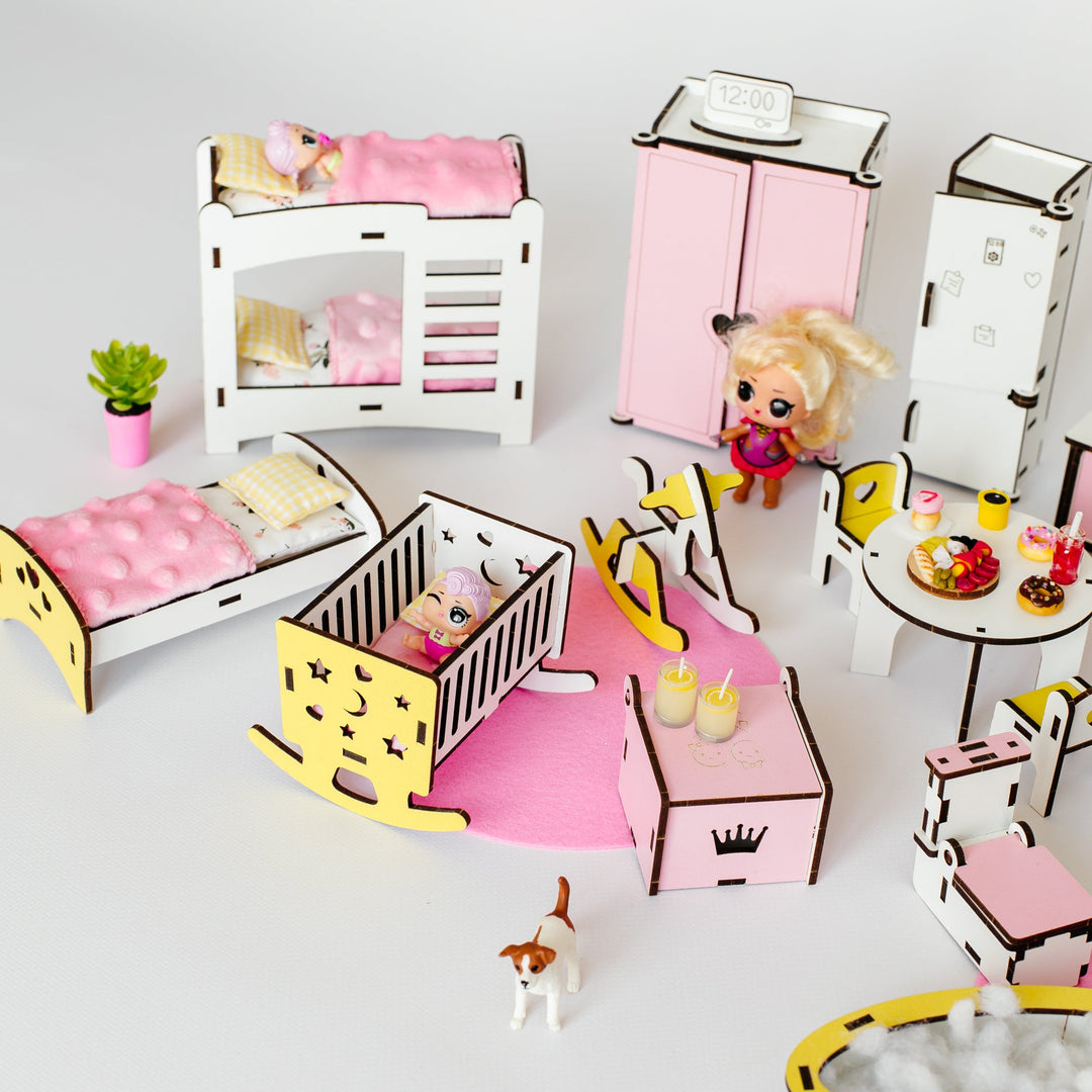 A dollhouse playset featuring miniature furniture and accessories in pink, white, and yellow, including beds, a wardrobe, a dining table, a rocking horse, and small animal figurines, arranged on a light gray background.