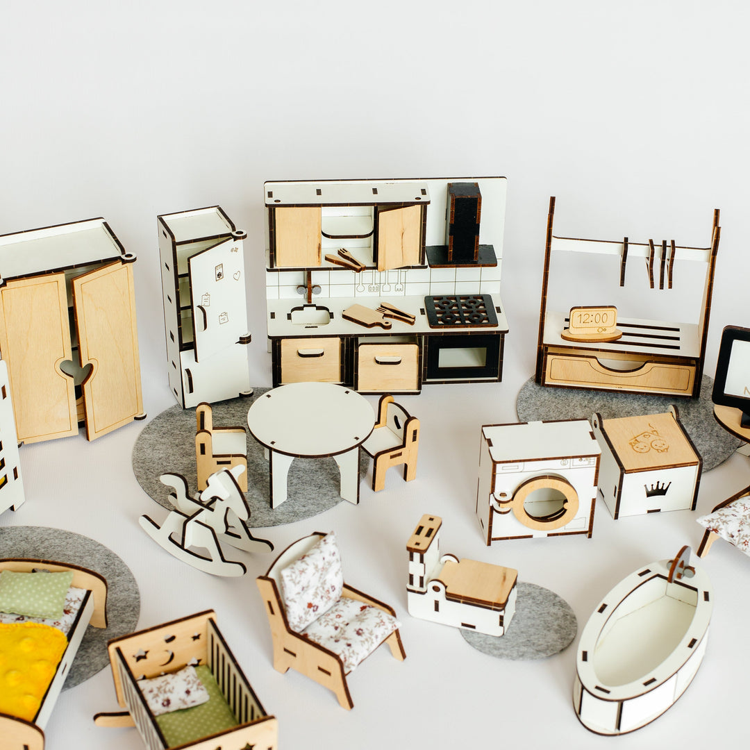 A collection of miniature wooden dollhouse furniture and kitchen accessories arranged on a light gray surface against a white background.