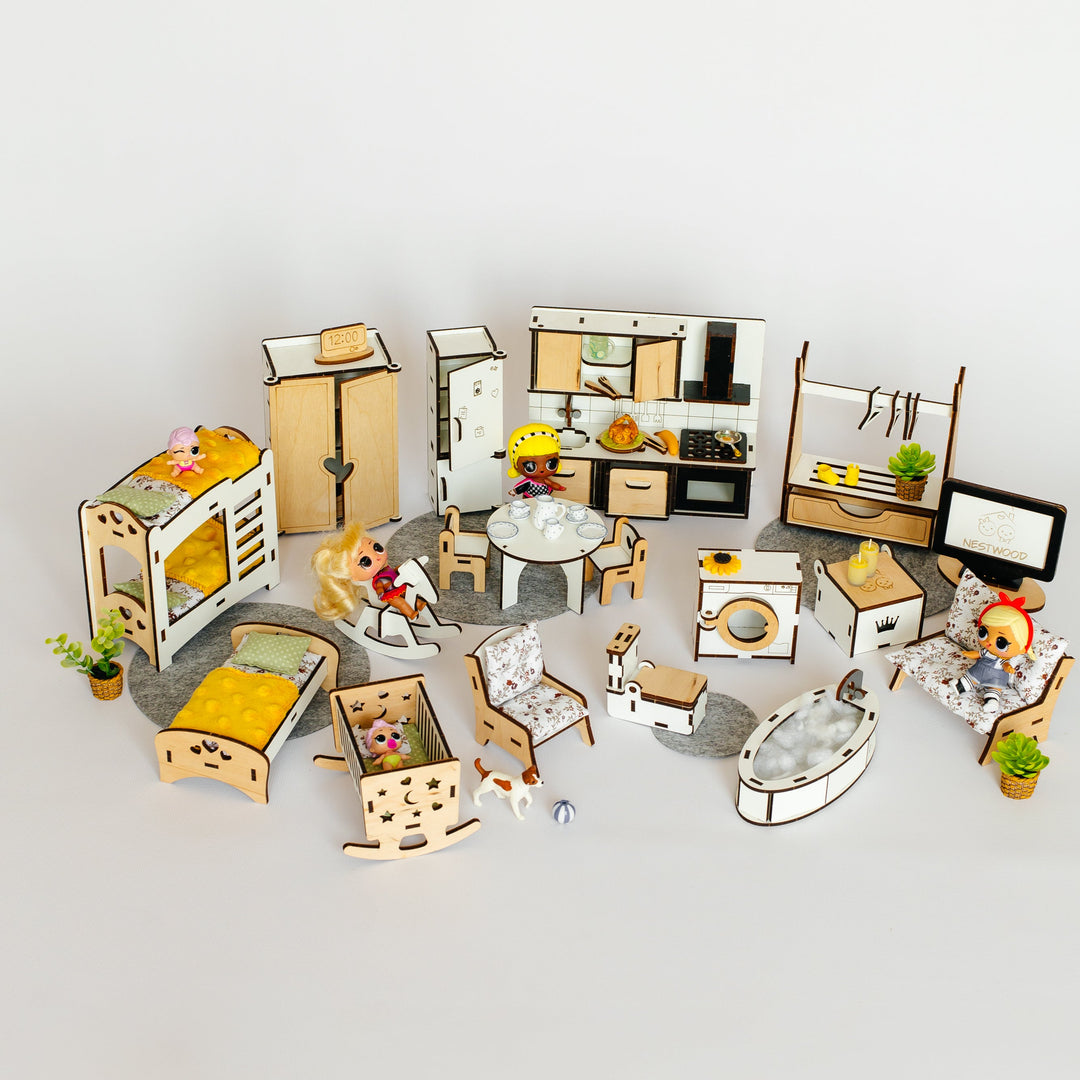 A miniature dollhouse furniture set arranged on a light gray surface against a white background. The set includes small beds, tables, chairs, cabinets, a kitchen, a washing machine, a computer desk, and tiny potted plants, with some pieces showing small doll figures.