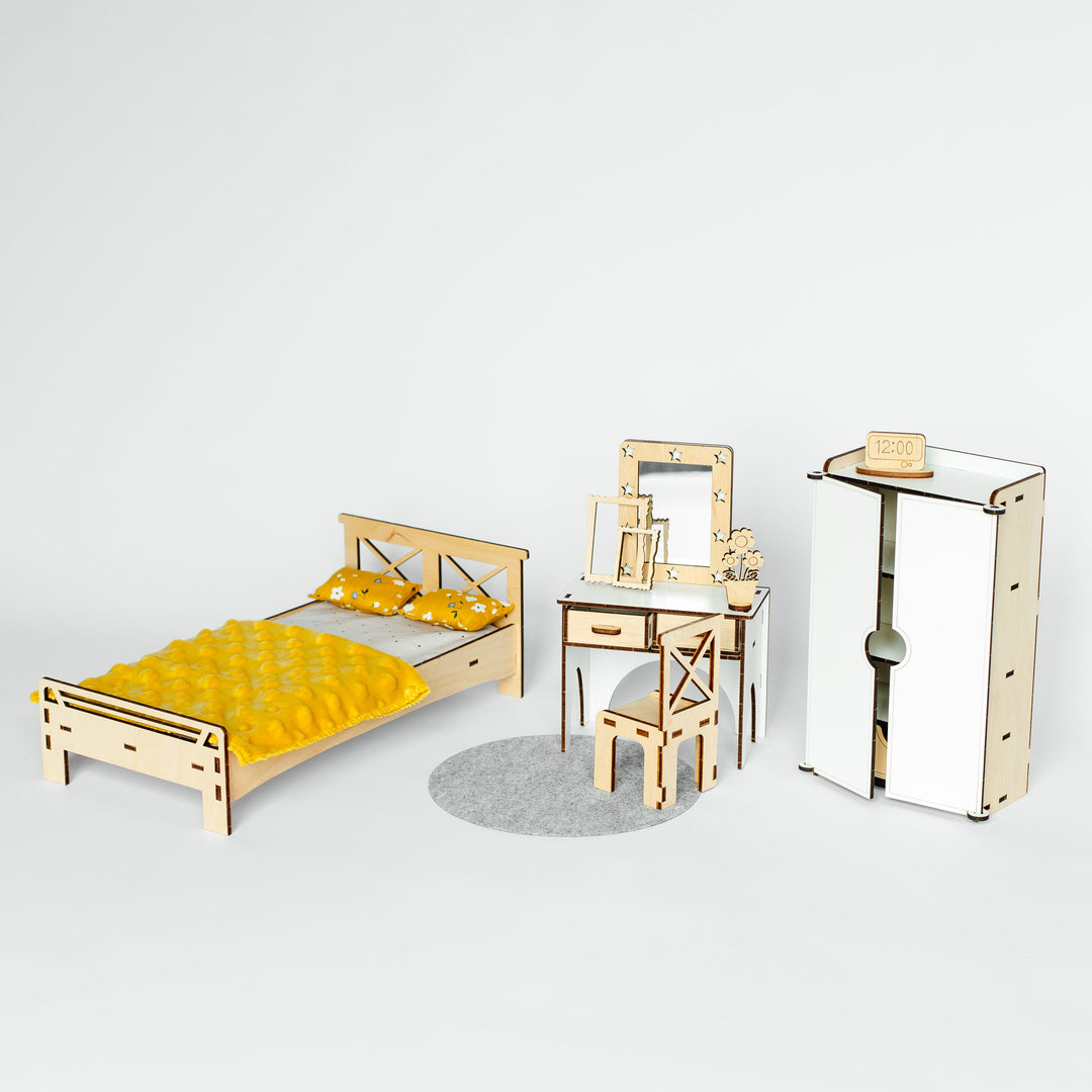 A miniature dollhouse furniture set featuring a bed with yellow bedding, a wooden vanity table with mirror and chair, and a tall wardrobe, displayed on a light gray background.
