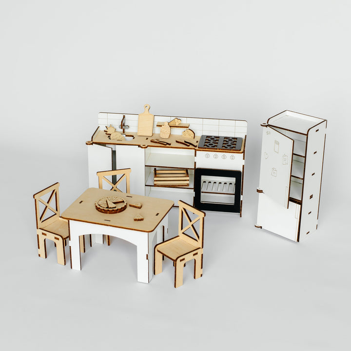 A miniature wooden dollhouse kitchen set featuring a white and wood dining table with four matching chairs, a kitchen counter with stove and oven, and a tall refrigerator, all shown on a light gray background.