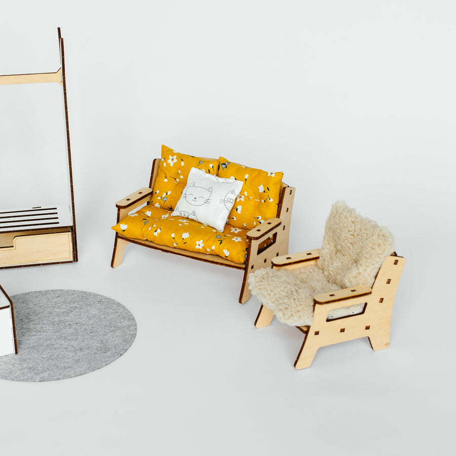 A miniature wooden loveseat and matching armchair set with yellow patterned cushions and a white throw pillow, displayed on a light gray background.