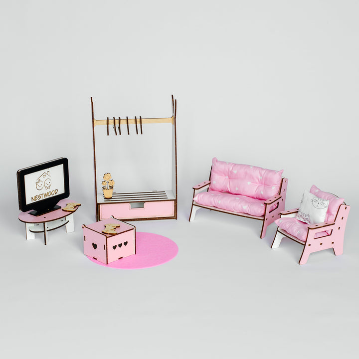 A miniature dollhouse furniture set in pink and brown, including a sofa, armchair, clothing rack, desk with a TV, and a small pink rug, displayed on a light gray background.