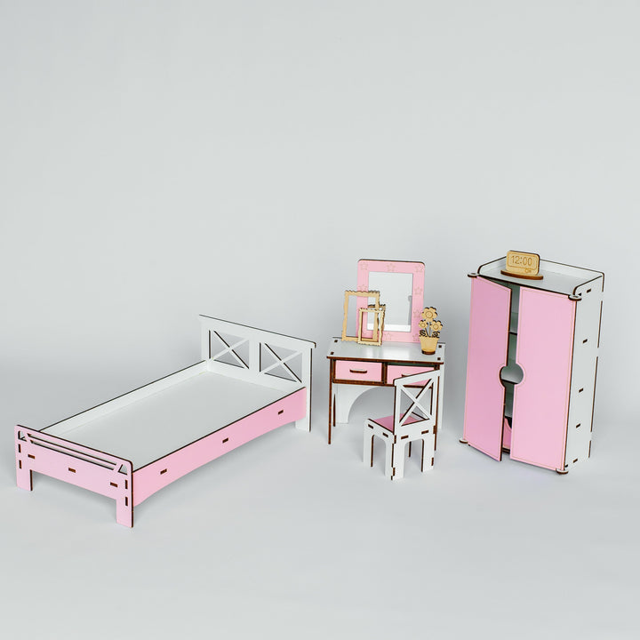 A miniature dollhouse furniture set featuring a pink and white single bed, a matching pink and white vanity table with a chair, and a pink and white wardrobe, displayed on a light gray background.