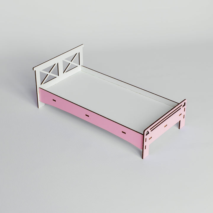 A small wooden bed frame with a pink footboard and white headboard, shown on a light gray studio background.