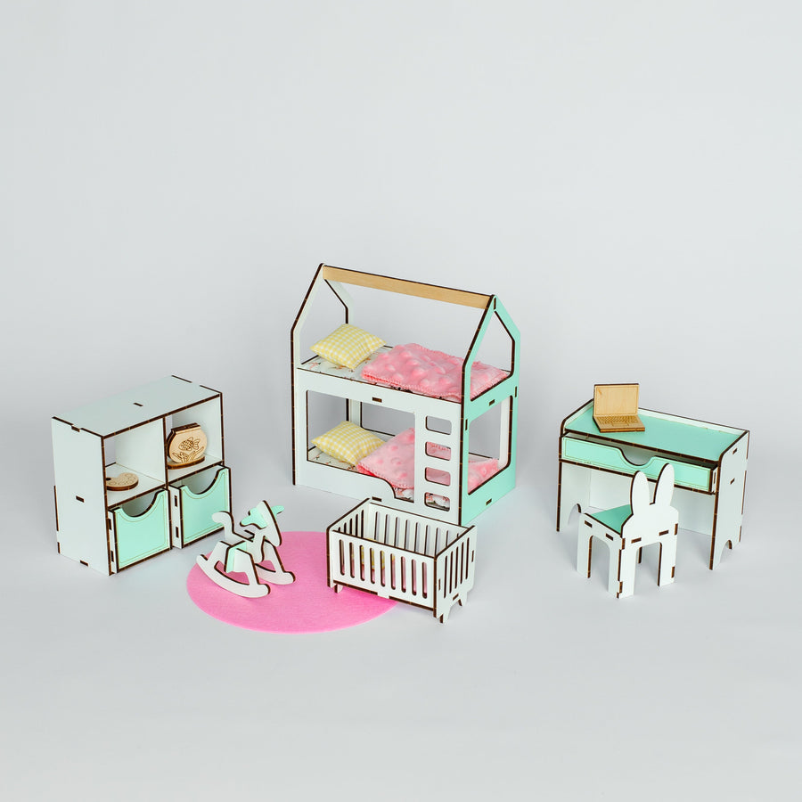 A miniature dollhouse-style nursery furniture set on a light gray background, including a house-shaped bed with pink bedding, a crib, a desk with chair, and storage cabinets.