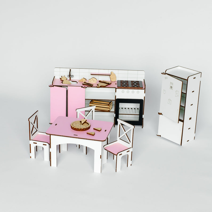 A miniature dollhouse kitchen set with a pink table and chairs, a white and pink kitchen unit, and a white cabinet, displayed on a light gray background.