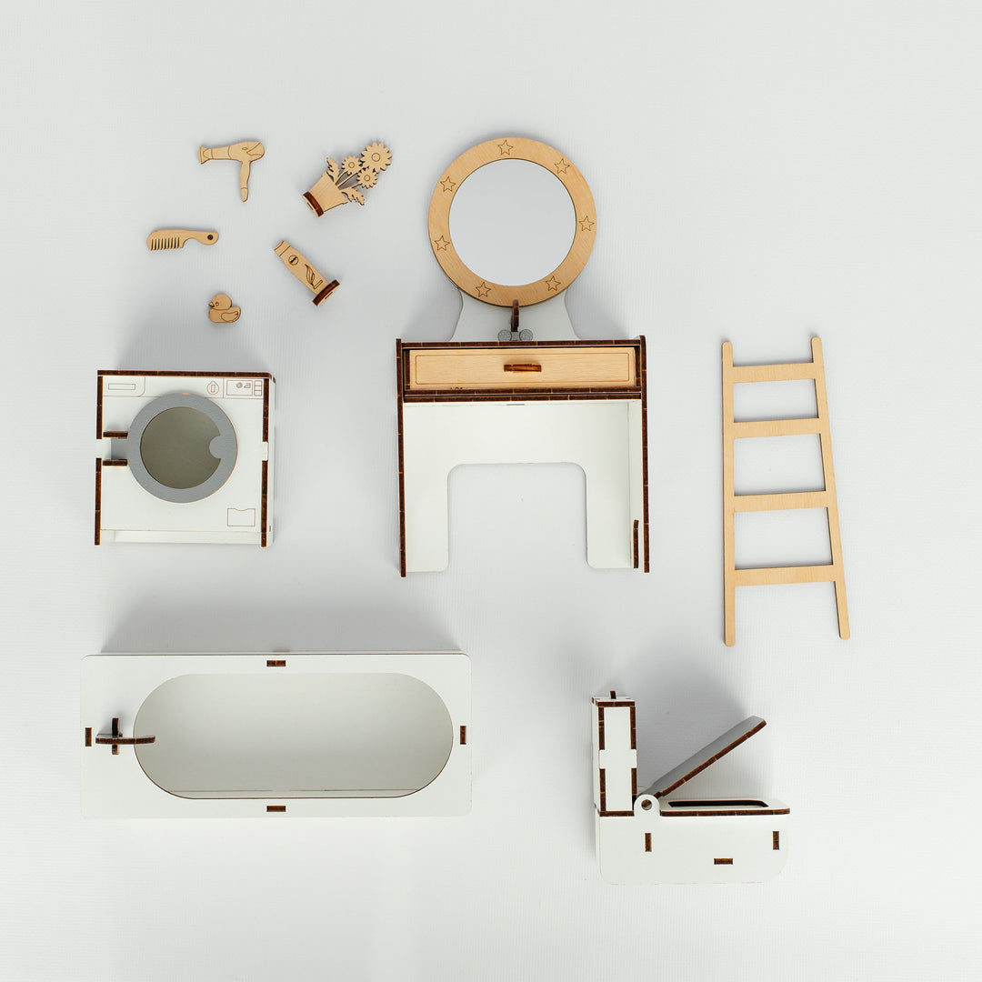 A minimalist wooden toy bathroom set arranged on a clean white background, including a bathtub, washing machine, vanity table with mirror, ladder, toilet, and small accessories.