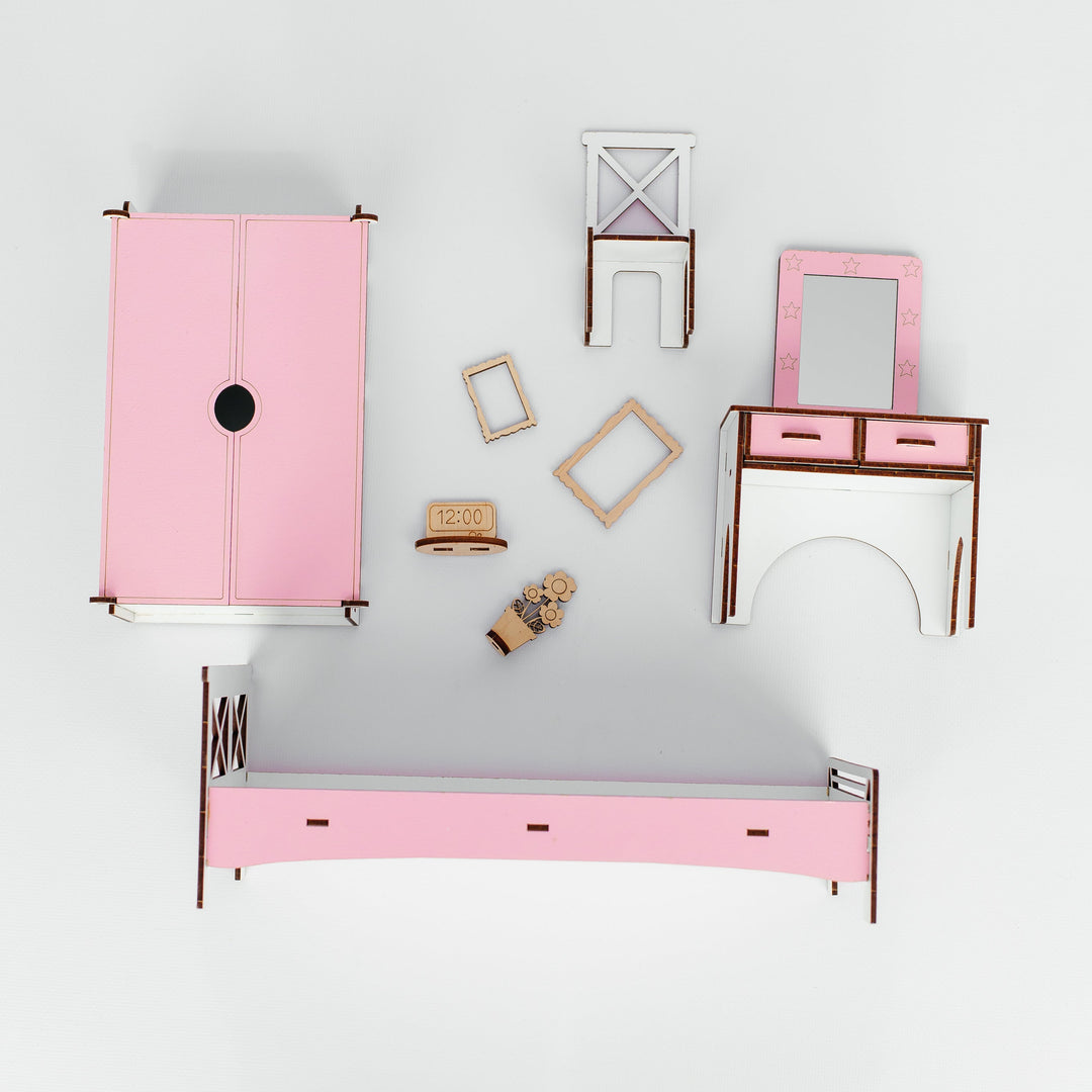 A dollhouse furniture set arranged on a light gray background, featuring a pink wardrobe, a pink bed frame, a pink vanity table with mirror, and other matching accessories.