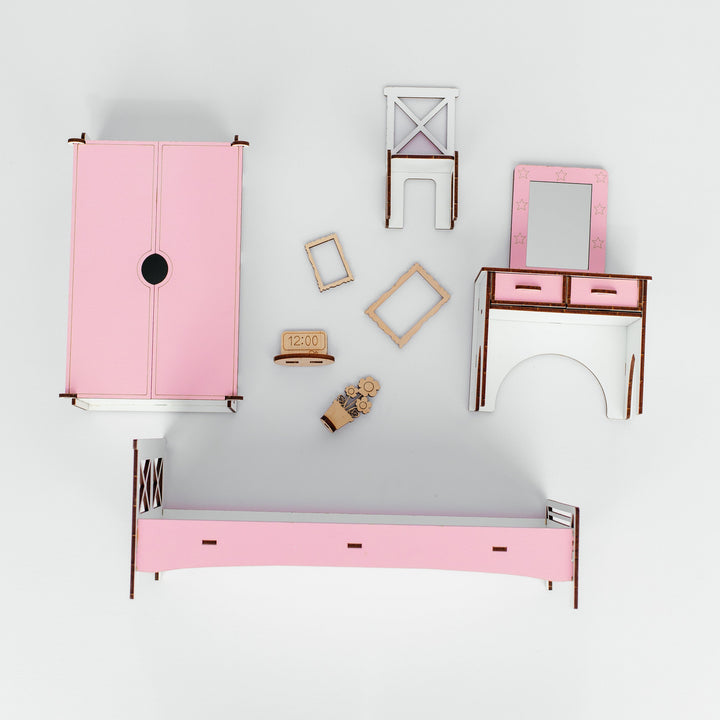 A dollhouse furniture set arranged on a light gray background, featuring a pink wardrobe, a pink bed frame, a pink vanity table with mirror, and other matching accessories.
