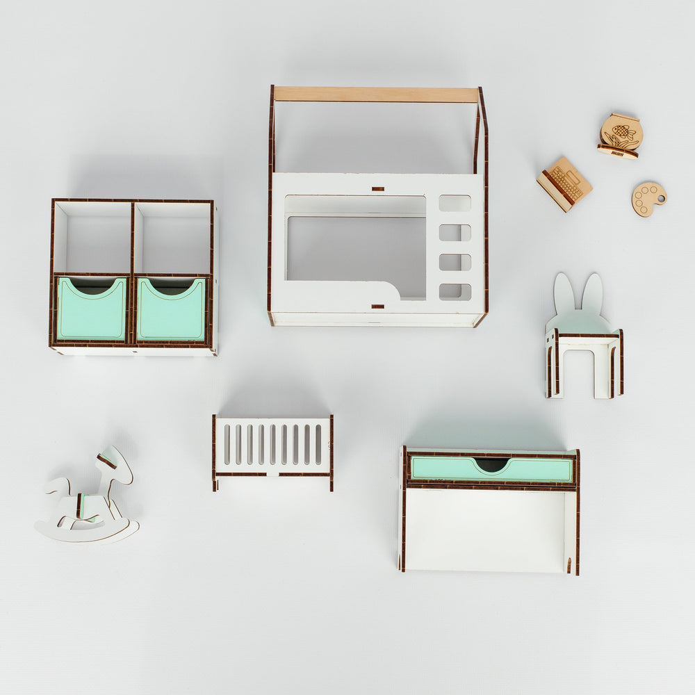 A top-down view of a dollhouse furniture set featuring a white and light wood play kitchen, crib, changing table, bunny chair, and storage units with mint green accents, arranged on a light gray background.