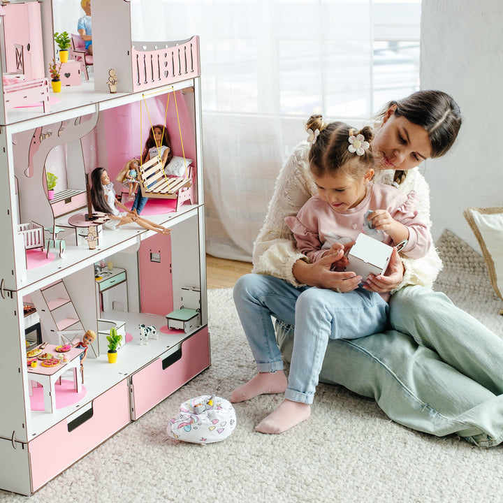 Mother and daughter playing with a dollhouse in a bright room.