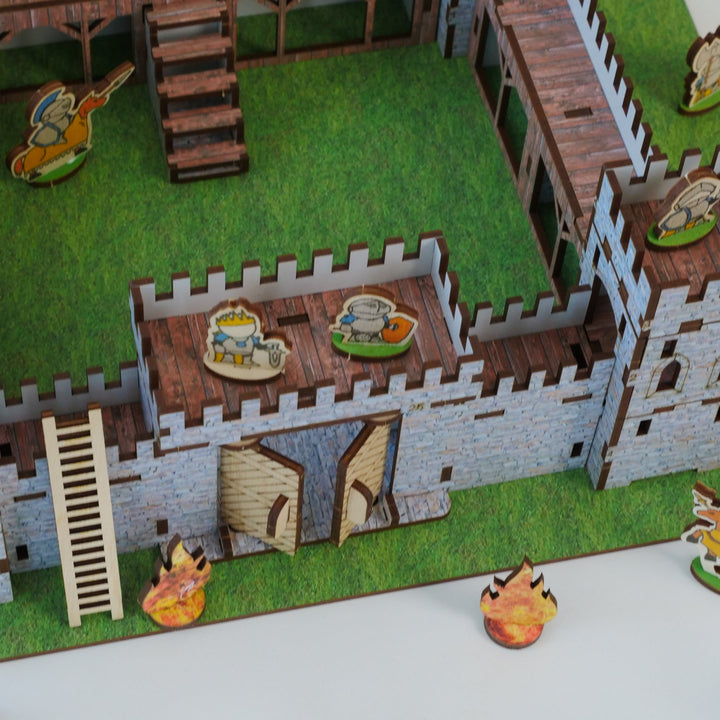 Model of a castle with detailed roof and ground level, featuring small figures and objects.