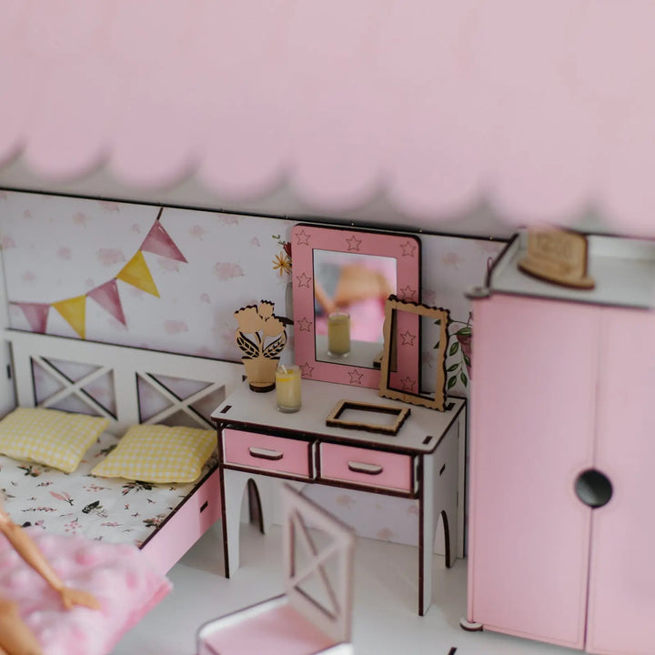 Miniature dollhouse bedroom with pink furniture and decor.