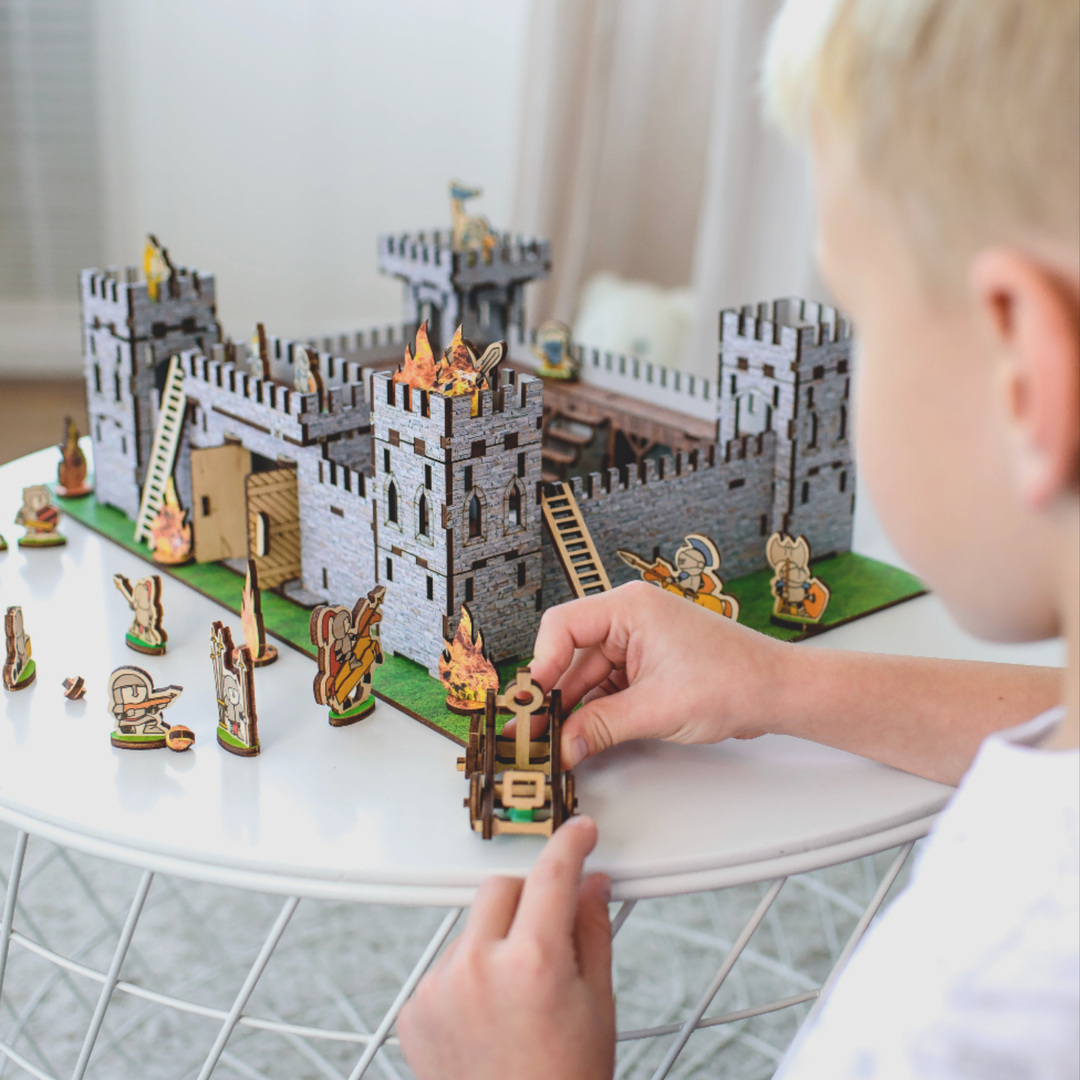 Child playing with a castle toy set on a table