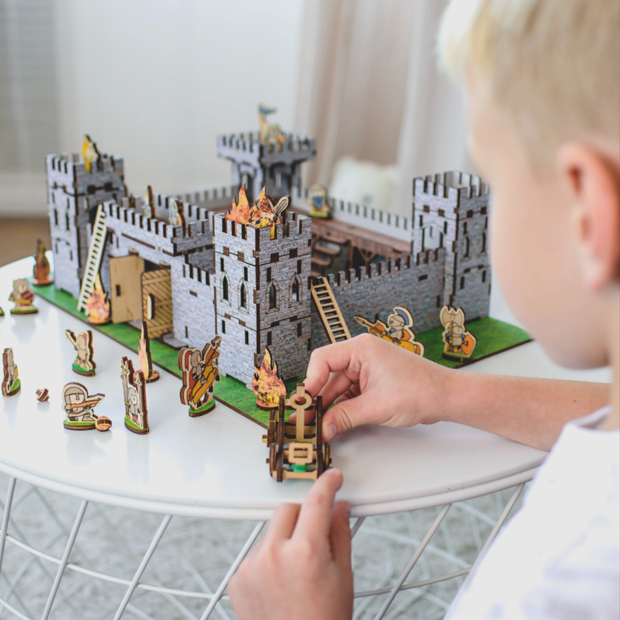 Child playing with a castle toy set on a table