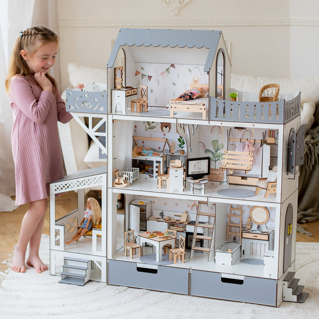 A child playing with a big gray wooden dollhouse with balcony and terrace. The dollhouse is multistory and has furniture inside.