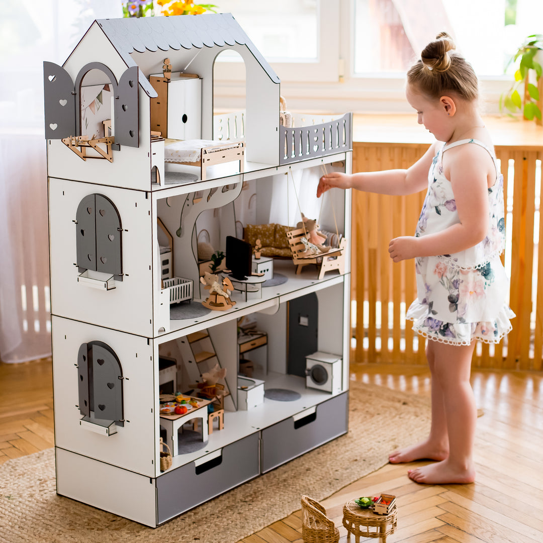 A beige and white dollhouse with a child arranging a small doll in a room, showcasing the product's use.